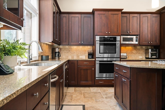 1303 Towsley Ln, Ann Arbor, MI 48105 - kitchen featuring appliances with stainless steel finishes, a sink, backsplash, stone finish flooring, and light stone counters