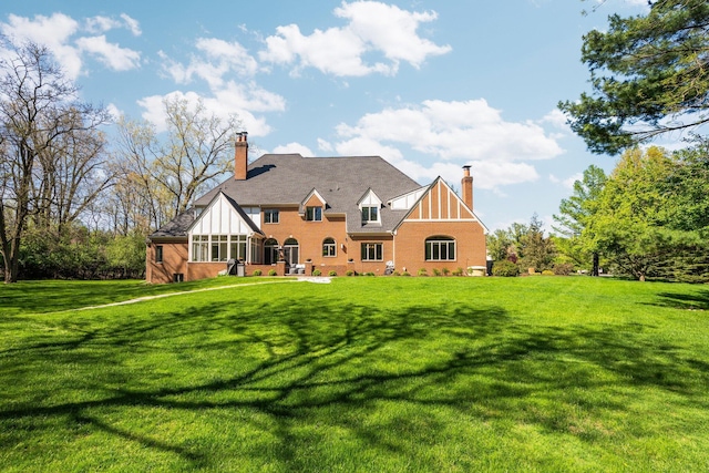 1303 Towsley Ln, Ann Arbor, MI 48105 - back of house featuring a chimney, a lawn, and brick siding