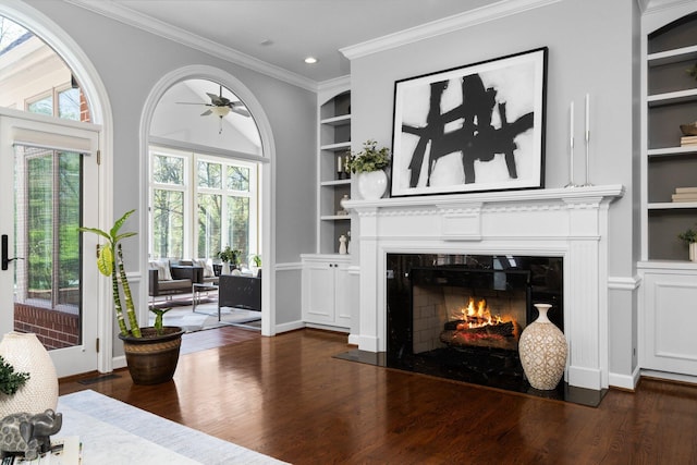 1303 Towsley Ln, Ann Arbor, MI 48105 - living area featuring built in shelves, a fireplace with flush hearth, dark wood-style floors, ceiling fan, and ornamental molding