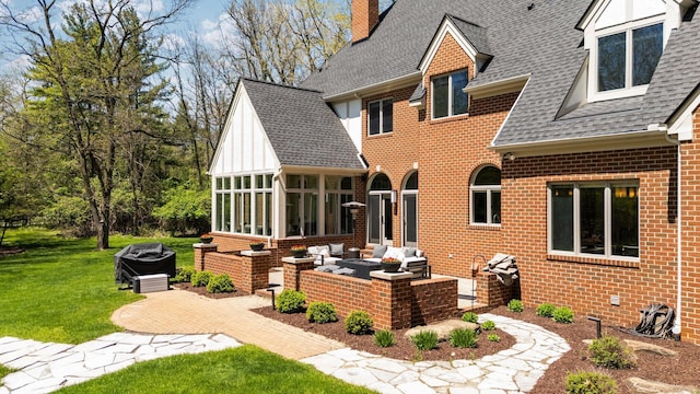 1303 Towsley Ln, Ann Arbor, MI 48105 - rear view of house with a shingled roof, a sunroom, brick siding, a patio area, and a chimney
