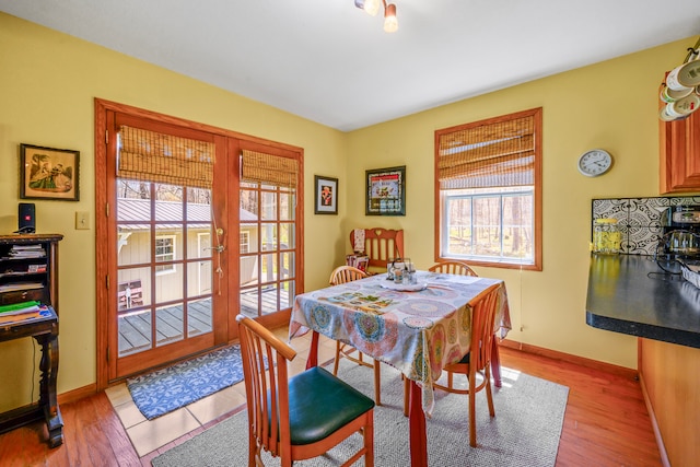 dining space featuring light wood finished floors, baseboards, and french doors
