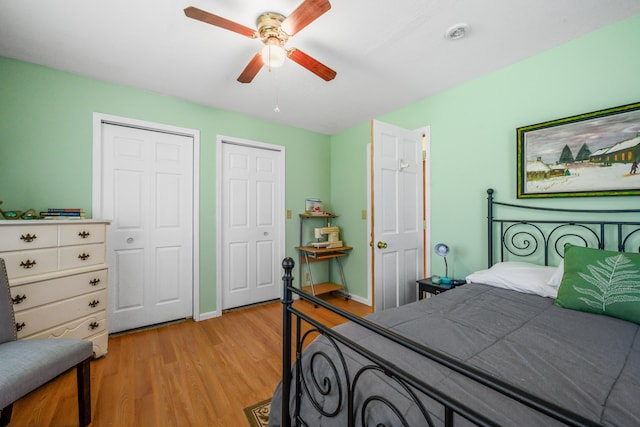 bedroom featuring multiple closets, light wood-style flooring, baseboards, and a ceiling fan