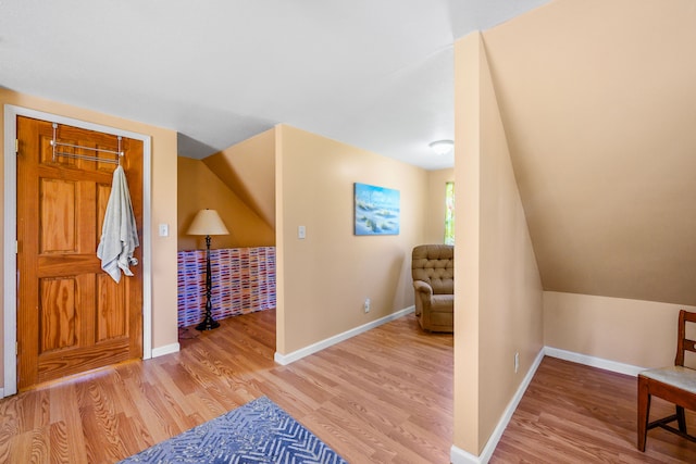 entryway with wood finished floors, baseboards, and vaulted ceiling