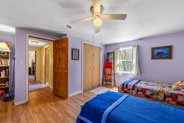 bedroom featuring light wood-style floors, a ceiling fan, baseboards, and a closet