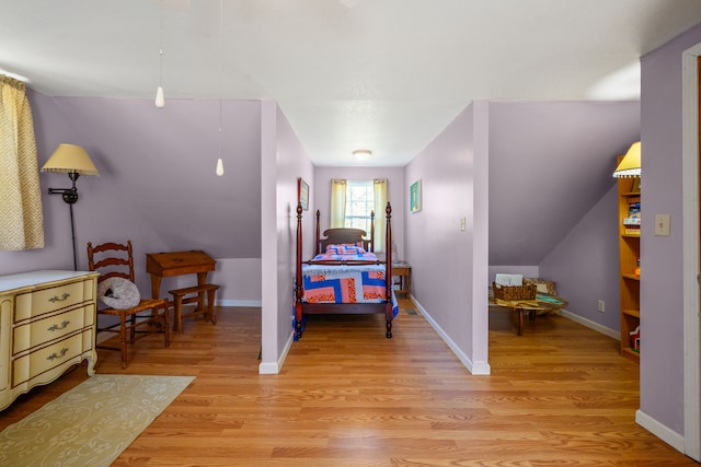 bedroom with light wood-type flooring, baseboards, and lofted ceiling