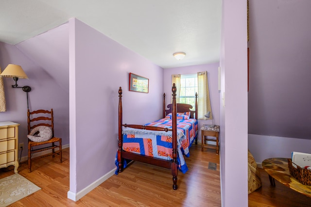 bedroom with light wood-style floors, baseboards, and lofted ceiling