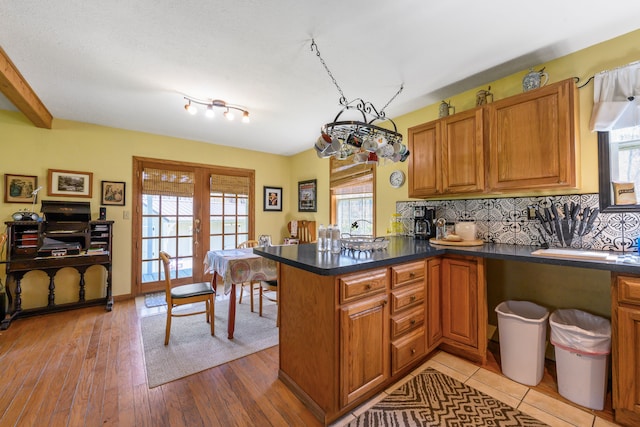 kitchen featuring a peninsula, brown cabinets, backsplash, and plenty of natural light