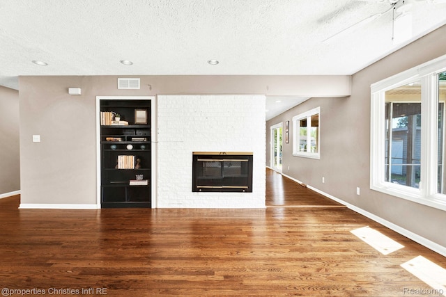 1700 Maddy Ln, Keego Harbor, MI 48320 - unfurnished living room with a textured ceiling, wood finished floors, a brick fireplace, built in shelves, and recessed lighting