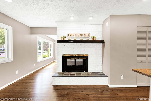 1700 Maddy Ln, Keego Harbor, MI 48320 - unfurnished living room featuring wood finished floors, a fireplace, and a textured ceiling