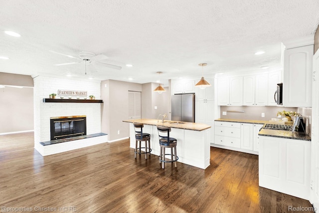 1700 Maddy Ln, Keego Harbor, MI 48320 - kitchen with stainless steel appliances, ceiling fan, white cabinetry, a textured ceiling, and a breakfast bar