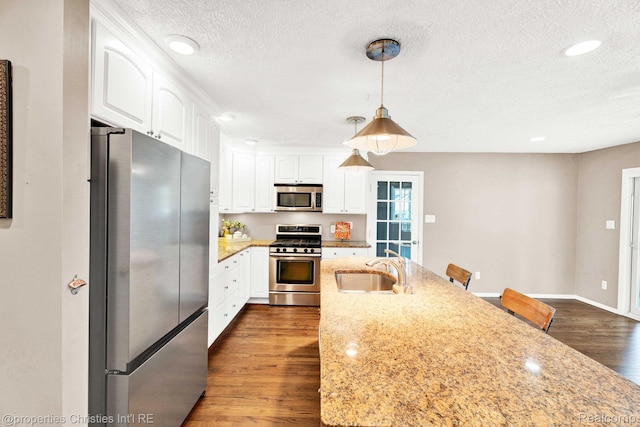 1700 Maddy Ln, Keego Harbor, MI 48320 - kitchen with stainless steel appliances, a textured ceiling, white cabinetry, dark wood-type flooring, and decorative light fixtures