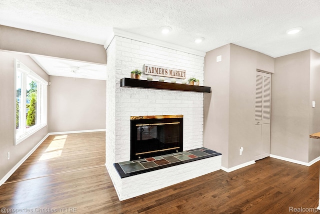 1700 Maddy Ln, Keego Harbor, MI 48320 - unfurnished living room with wood finished floors, a brick fireplace, a textured ceiling, and a ceiling fan