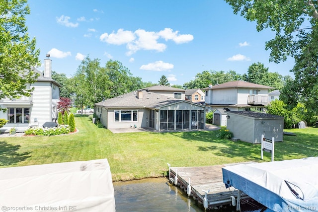 1700 Maddy Ln, Keego Harbor, MI 48320 - rear view of house featuring a storage shed, a sunroom, a lawn, and a water view