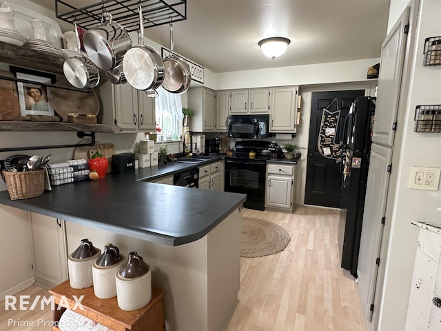 1321 Rollins St, Grand Blanc, MI 48439 - kitchen with black appliances, dark countertops, a sink, a peninsula, and light wood finished floors