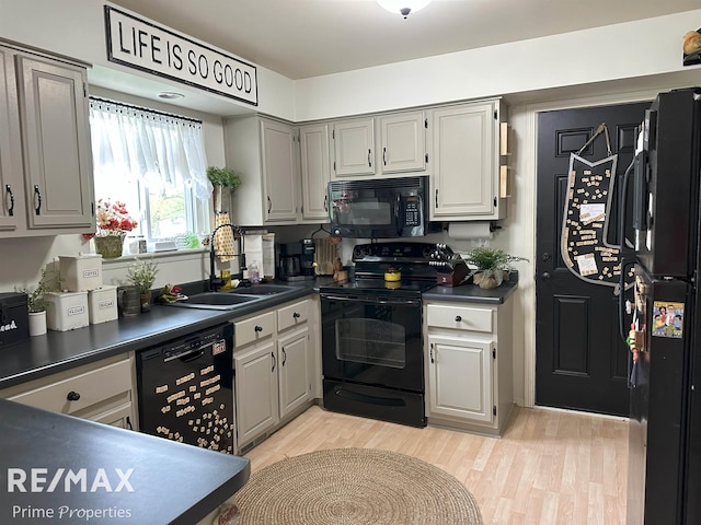 1321 Rollins St, Grand Blanc, MI 48439 - kitchen with black appliances, a sink, dark countertops, and light wood-style flooring