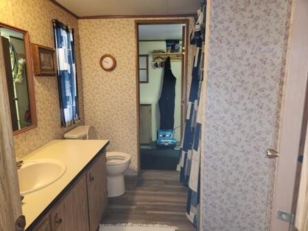 4297 N Wilderness Trl, Luther, MI 49656 - bathroom featuring wood finished floors, ornamental molding, wallpapered walls, toilet, and vanity