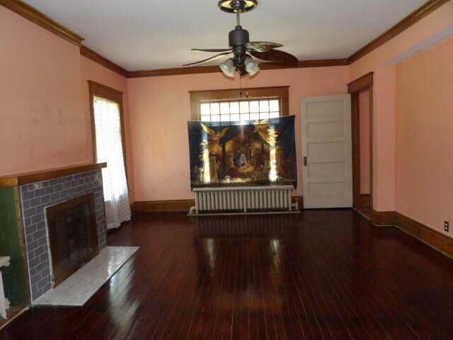 31 Orchard Pl, Battle Creek, MI 49017 - unfurnished living room with a tiled fireplace, ceiling fan, hardwood / wood-style flooring, ornamental molding, and baseboards