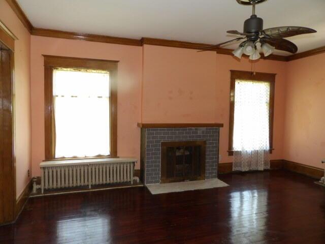 31 Orchard Pl, Battle Creek, MI 49017 - unfurnished living room with radiator, ceiling fan, ornamental molding, wood finished floors, and a tile fireplace