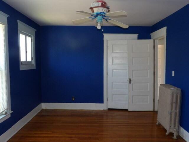 31 Orchard Pl, Battle Creek, MI 49017 - unfurnished room featuring radiator heating unit, ceiling fan, wood finished floors, and baseboards
