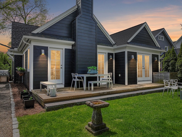 608 W Lincoln St, Birmingham, MI 48009 - back of property at dusk with french doors, a deck, a yard, roof with shingles, and a chimney