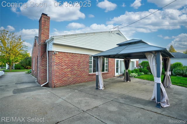 2302 Radcliffe Ave, Flint, MI 48503 - back of property with a chimney, a gazebo, brick siding, and a patio area