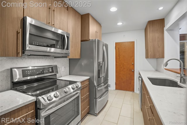 2302 Radcliffe Ave, Flint, MI 48503 - kitchen with appliances with stainless steel finishes, a sink, brown cabinets, light stone counters, and recessed lighting