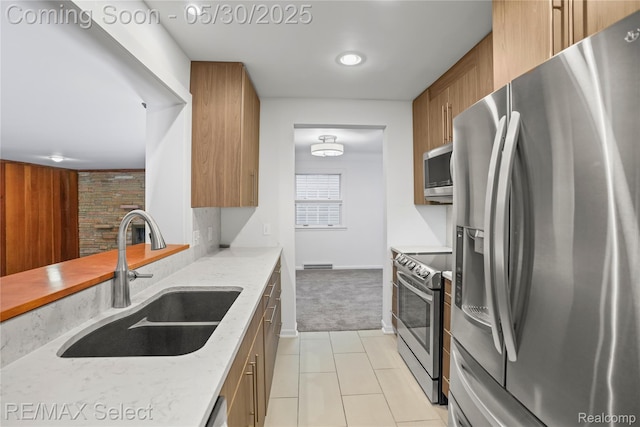 2302 Radcliffe Ave, Flint, MI 48503 - kitchen with stainless steel appliances, a sink, brown cabinets, light carpet, and light tile patterned floors