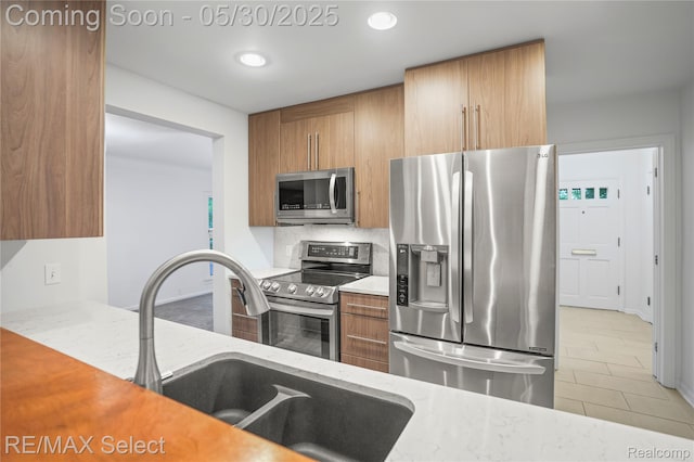 2302 Radcliffe Ave, Flint, MI 48503 - kitchen with appliances with stainless steel finishes, brown cabinetry, a sink, light stone countertops, and recessed lighting
