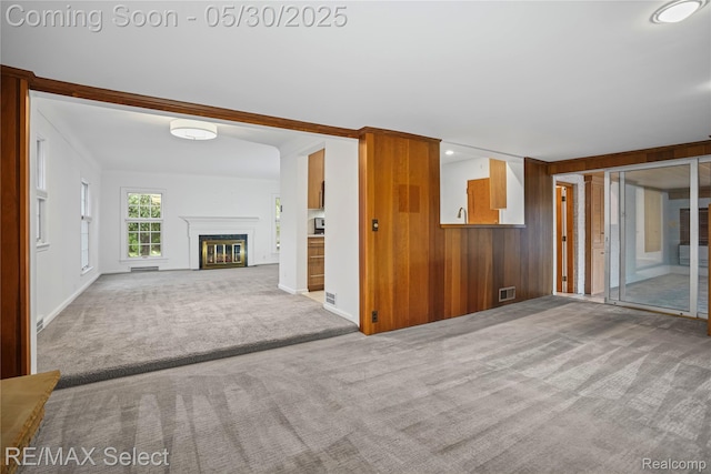 2302 Radcliffe Ave, Flint, MI 48503 - unfurnished living room featuring carpet flooring, a glass covered fireplace, and wooden walls