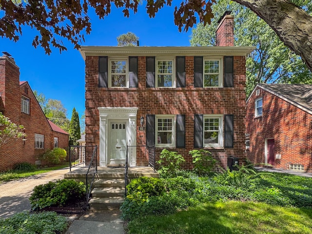 colonial house featuring brick siding and a chimney