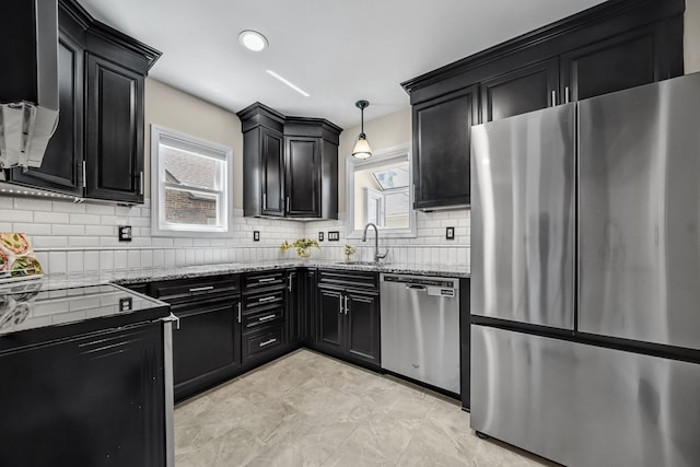 kitchen with stainless steel appliances, dark cabinets, light stone countertops, and tasteful backsplash