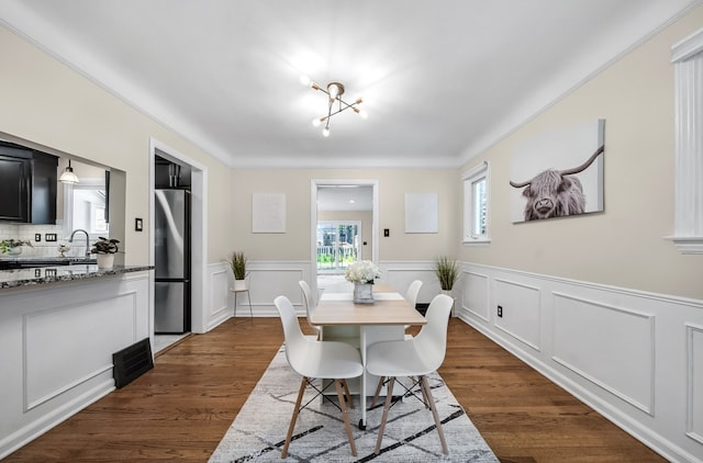 dining space featuring a wainscoted wall, dark wood-style flooring, and crown molding