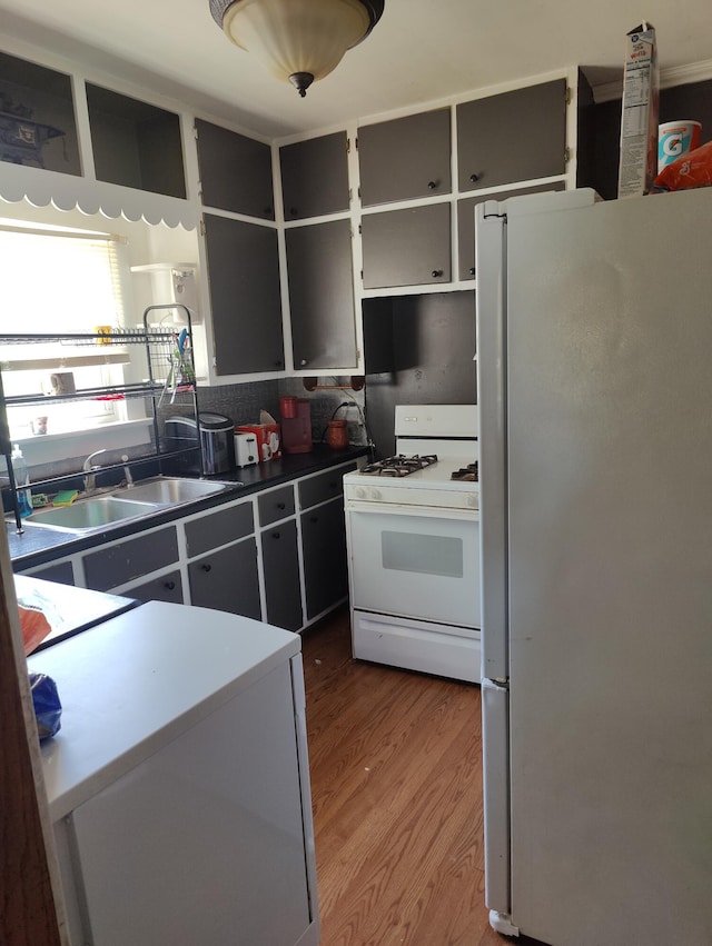 kitchen featuring white appliances, a sink, wood finished floors, and open shelves