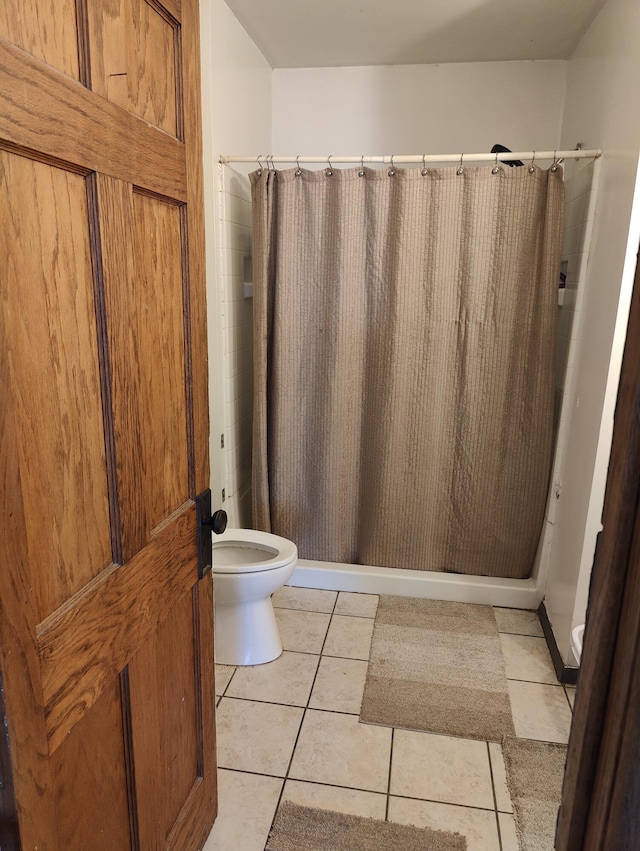 bathroom with toilet, a stall shower, and tile patterned floors