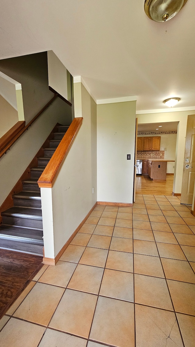 spare room featuring light tile patterned floors, stairway, baseboards, and crown molding