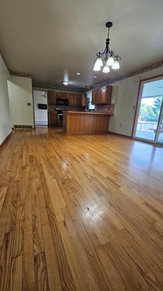 unfurnished living room featuring light wood-style floors and a chandelier
