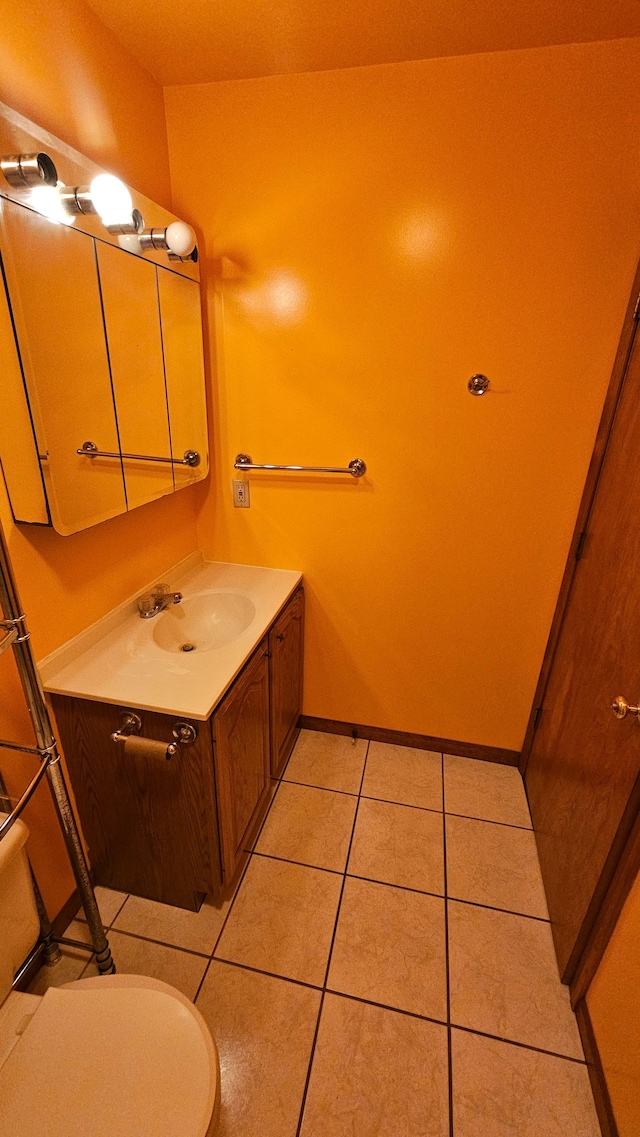 half bathroom with vanity, tile patterned floors, toilet, and baseboards