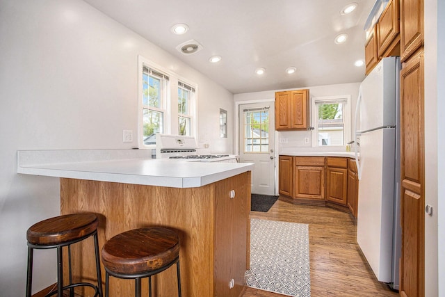 820 N Werners Landing Dr, Bronson, MI 49028 - kitchen featuring white appliances, a peninsula, light wood-type flooring, light countertops, and a breakfast bar area