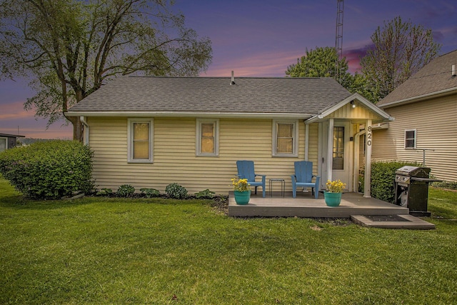 820 N Werners Landing Dr, Bronson, MI 49028 - back of property at dusk with a lawn, a deck, and a shingled roof