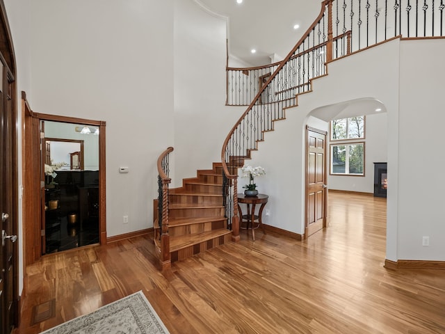1334 Larayne Dr, Troy, MI 48085 - stairs featuring baseboards, a glass covered fireplace, a high ceiling, wood finished floors, and recessed lighting
