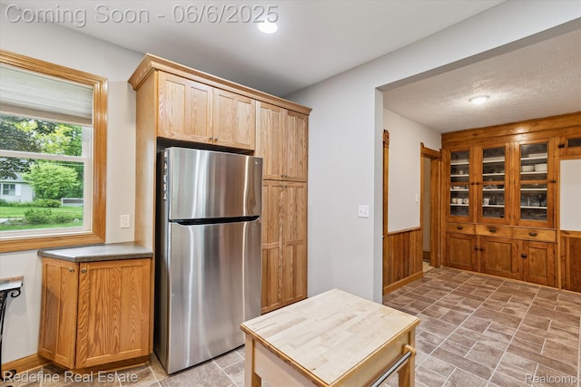 101 Hill St, Stockbridge, MI 49285 - kitchen featuring freestanding refrigerator, stone finish floors, a wainscoted wall, and wood walls