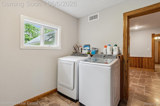 101 Hill St, Stockbridge, MI 49285 - laundry room featuring washing machine and clothes dryer, wood walls, wainscoting, baseboards, and stone finish floors