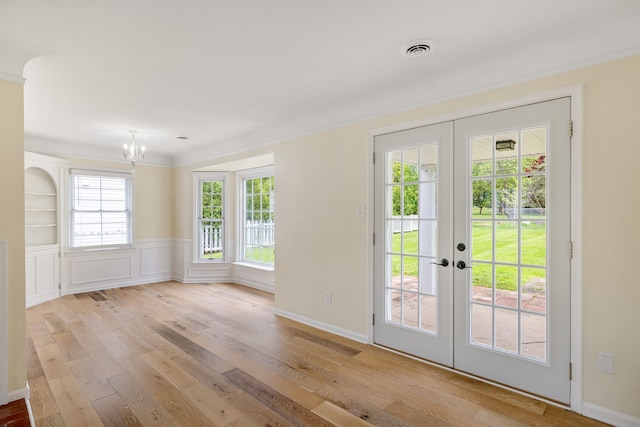 doorway to outside with ornamental molding, a chandelier, hardwood / wood-style floors, and french doors