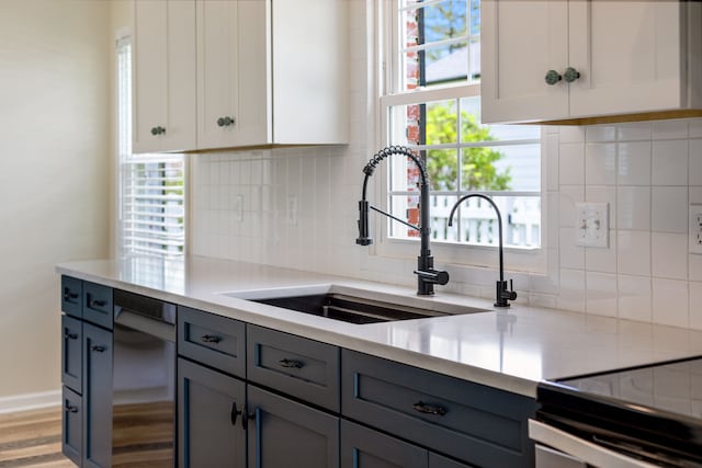 kitchen featuring a sink, gray cabinetry, backsplash, light countertops, and wood finished floors