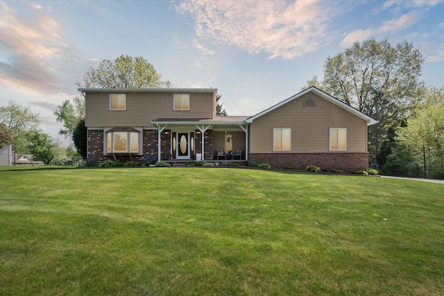 view of front facade featuring covered porch, brick siding, and a lawn