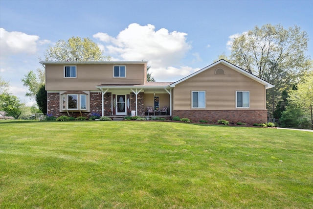 view of front of property with brick siding, covered porch, and a front lawn