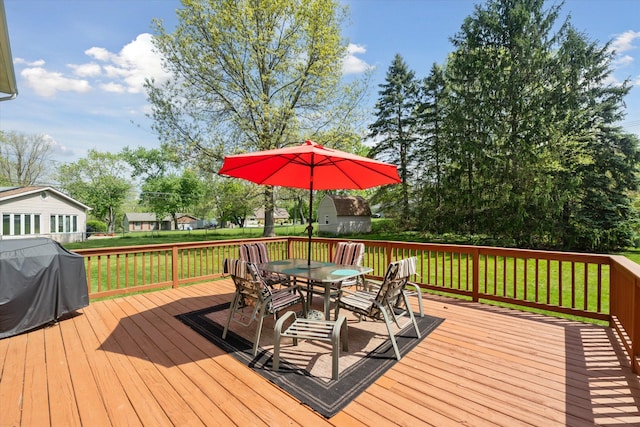 wooden terrace with outdoor dining area, grilling area, and a lawn