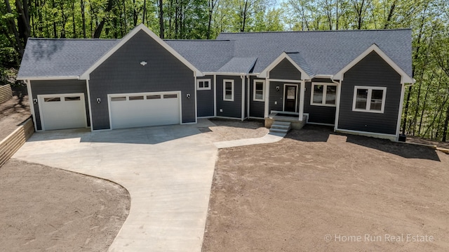 view of front of property featuring driveway, an attached garage, and roof with shingles