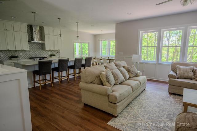 living area with dark wood finished floors, wainscoting, a decorative wall, and recessed lighting