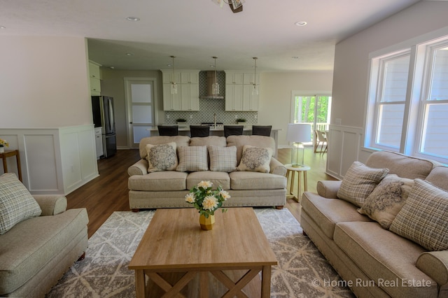 living room with wood finished floors, wainscoting, a decorative wall, and recessed lighting